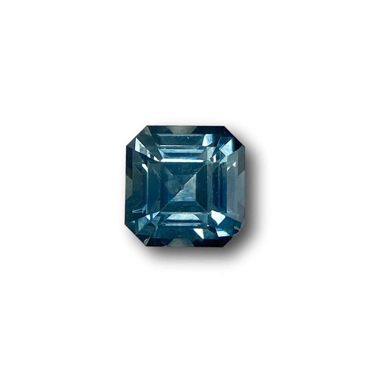 0.79ct blue Montana sapphire with a square Asscher cut, measuring 5.00 x 4.90mm against a white background.