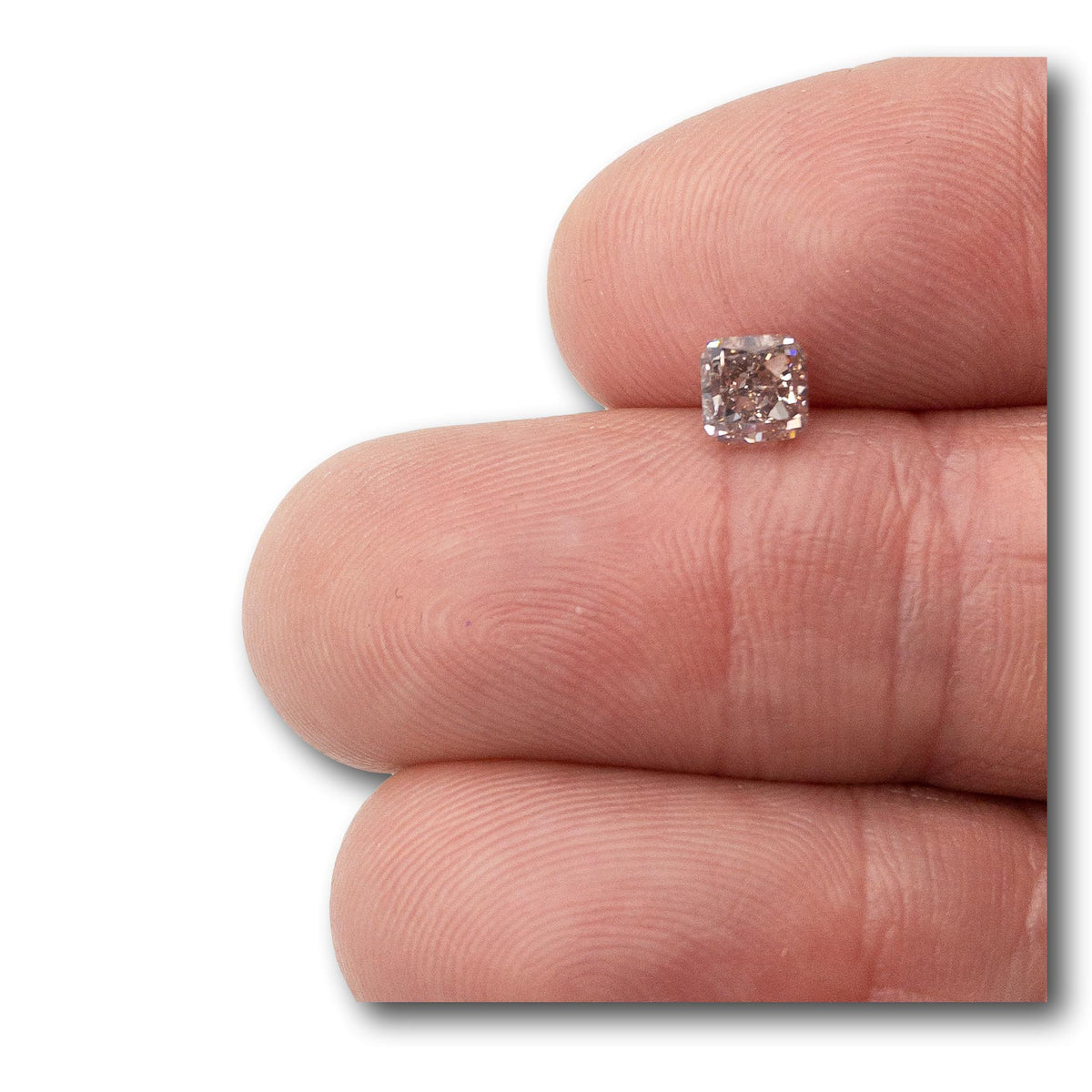 0.83ct cushion-cut fancy brownish pink diamond held between fingers, showing brilliant facets and VS2 clarity.