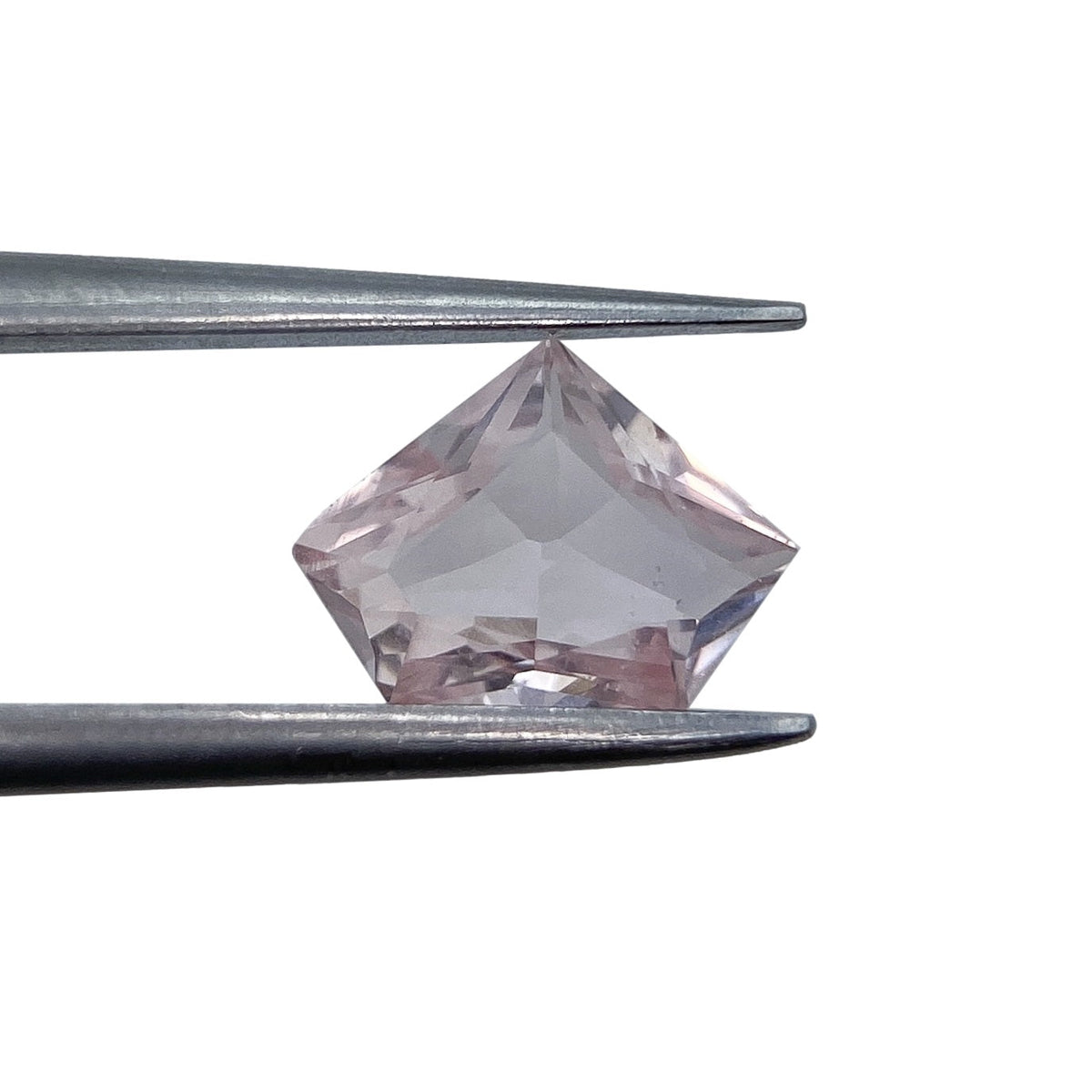 0.91ct brilliant cut pink sapphire in a unique shield shape held by metal tweezers against a white background.