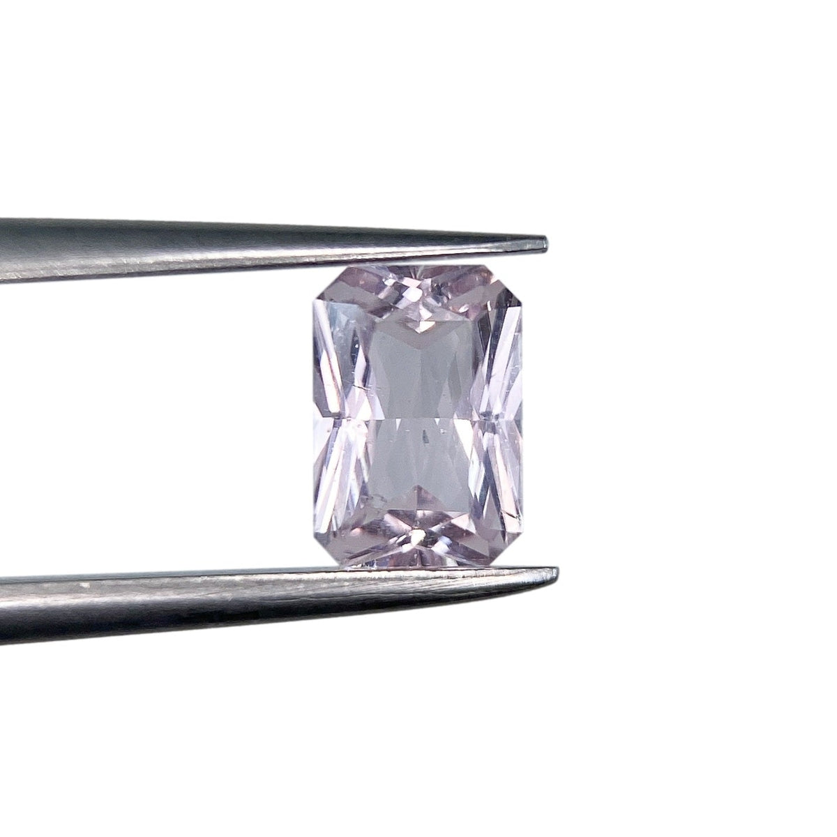 0.92ct radiant cut pink sapphire held in metal tweezers against a white background.
