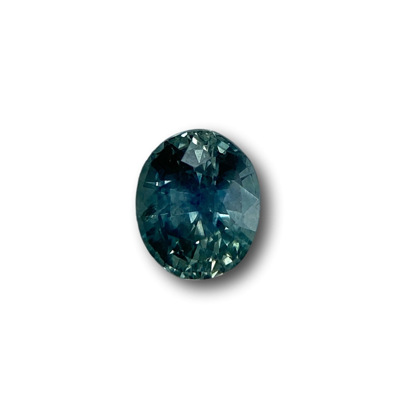 0.97ct oval brilliant cut blue Montana sapphire gemstone with deep teal facets on a white background.