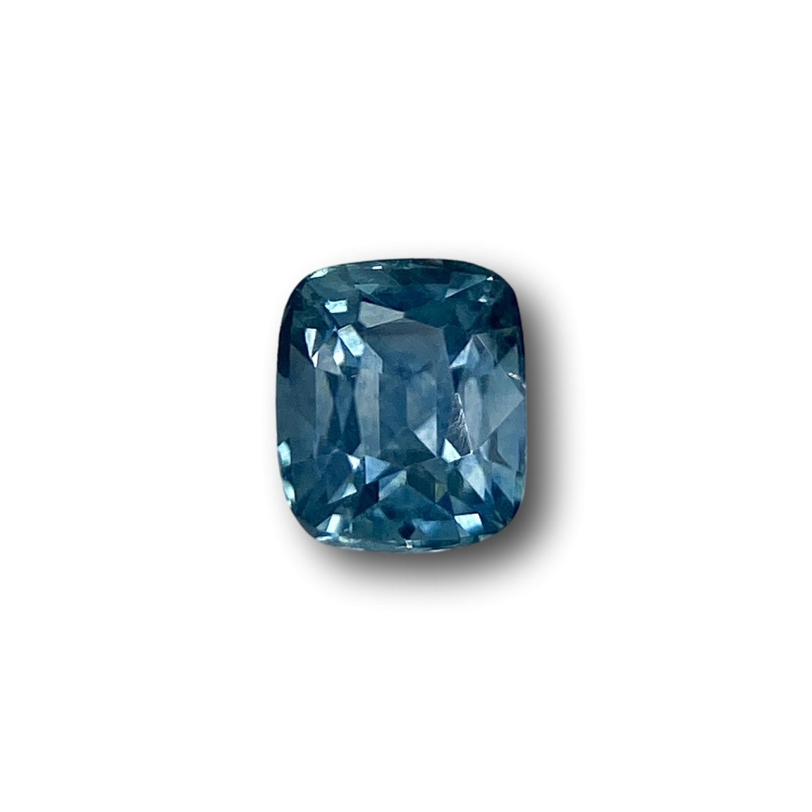 0.99ct cushion-cut blue Montana sapphire with a brilliant faceted surface isolated on a white background.
