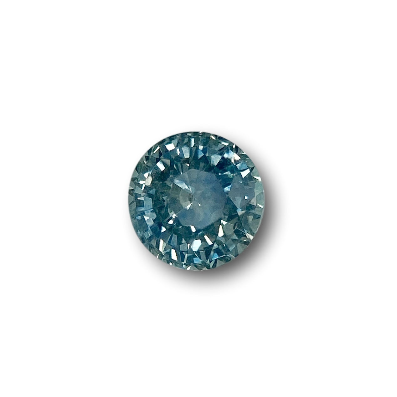 1.01ct round brilliant cut blue Montana sapphire gemstone with intricate facets isolated on white.