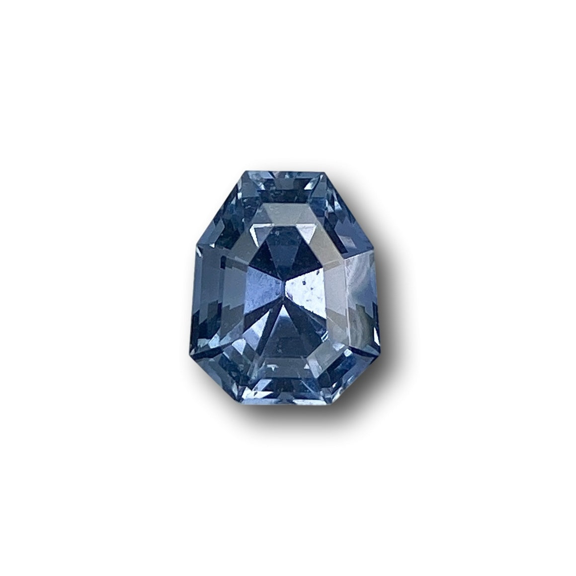 1.01ct blue sapphire with a step-cut shield shape, measuring 6.15 x 5.00 x 4.10 mm against a white background.