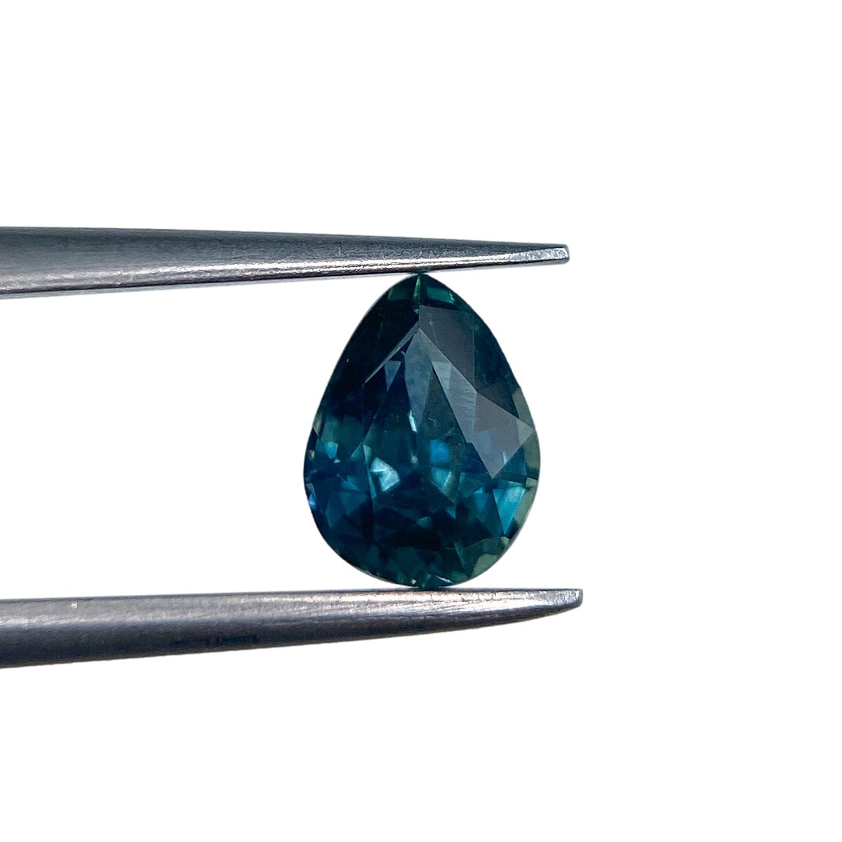 1.05ct pear-shaped blue Montana sapphire with a brilliant cut held in metal tweezers against a white background.