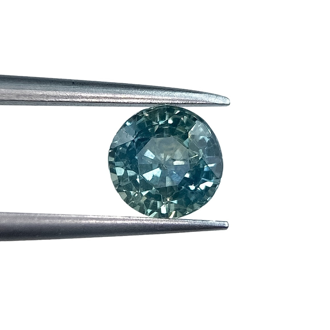 1.06ct round brilliant cut blue Montana sapphire held in metal tweezers against a white background.