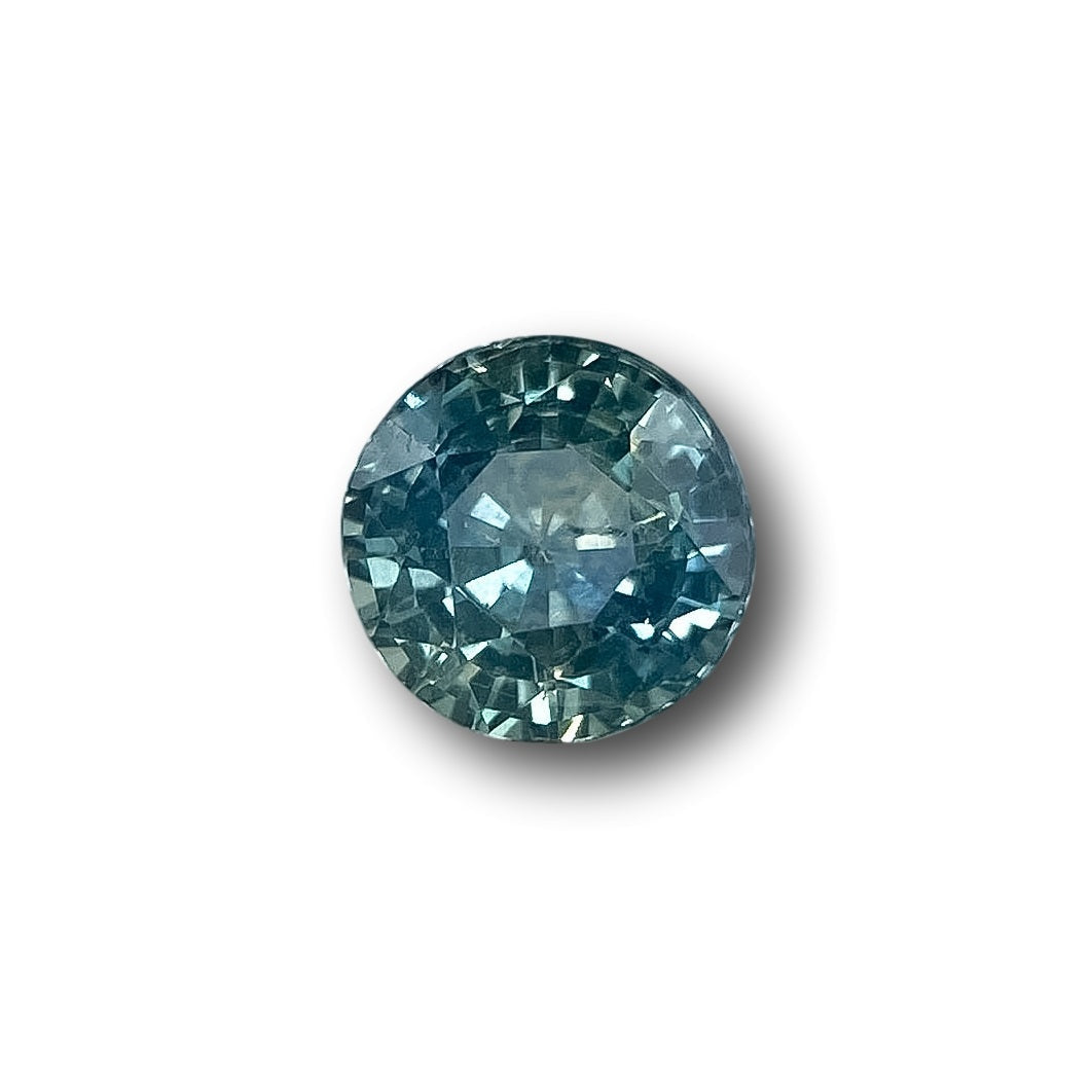 1.06ct round brilliant cut blue Montana sapphire gemstone with faceted surface on a white background.