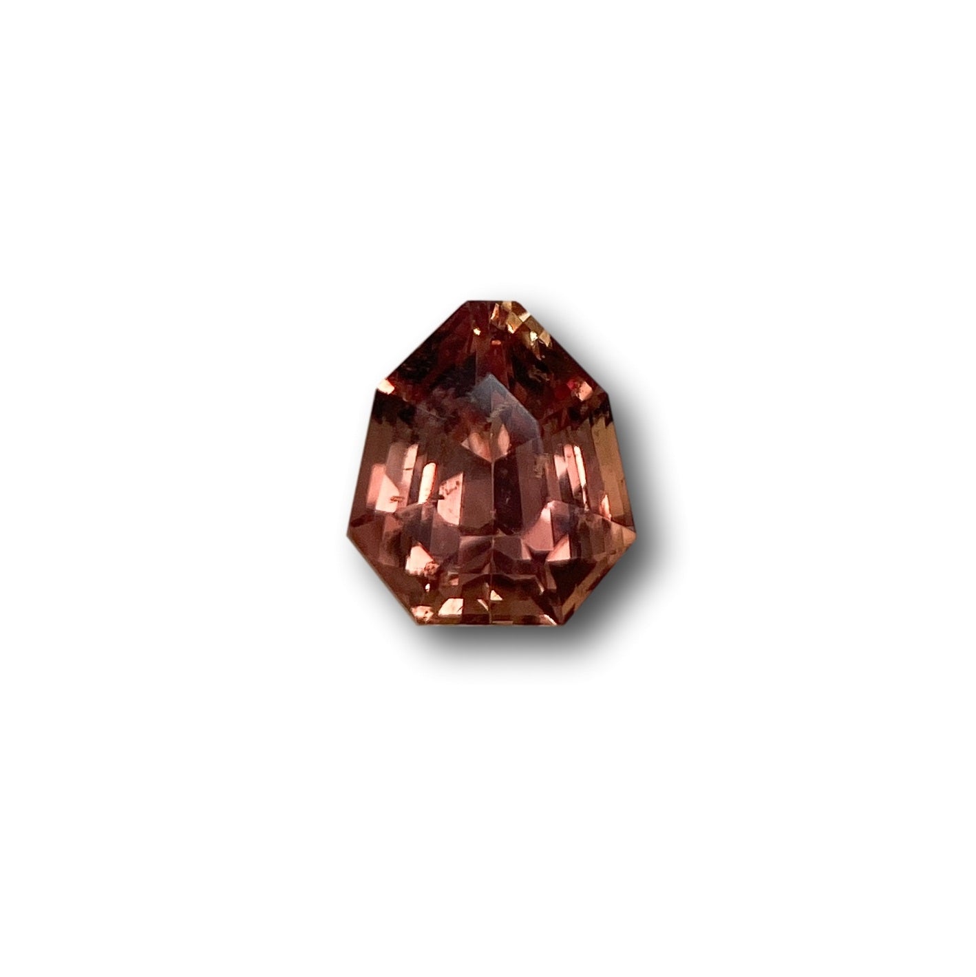 1.06ct brilliant cut brown sapphire with a unique shield shape and faceted surface on a white background.