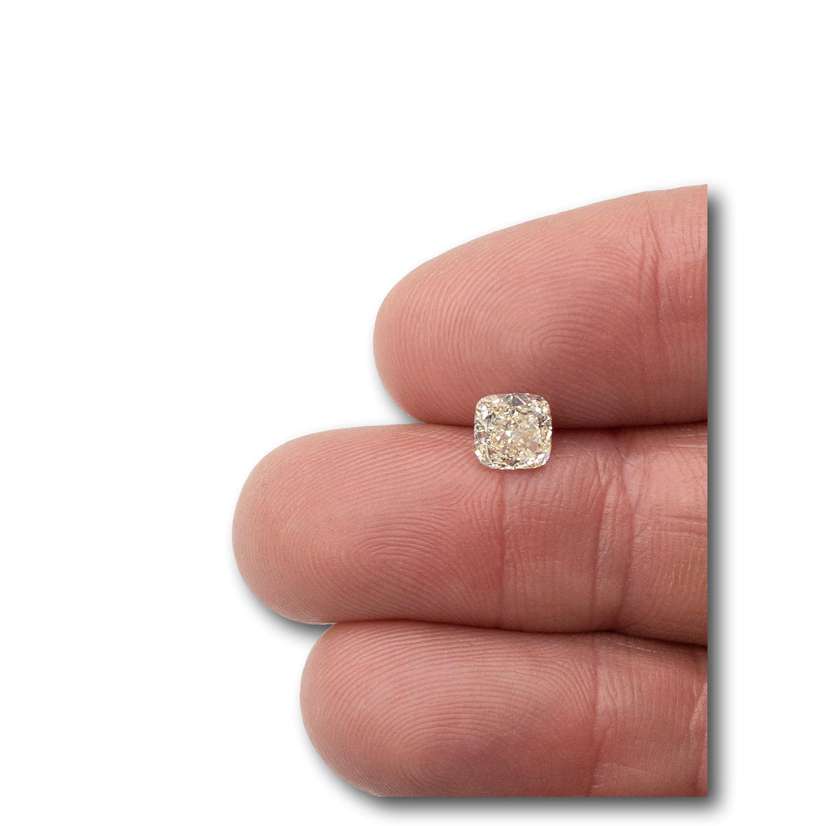 1.11ct cushion brilliant cut natural diamond with M color held between fingers.