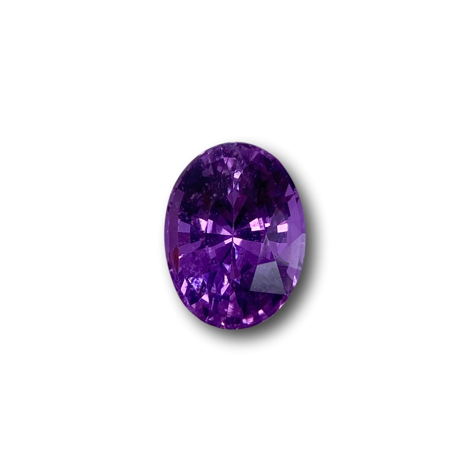 1.14ct oval-cut violet sapphire gemstone with a brilliant faceted surface isolated on a white background.