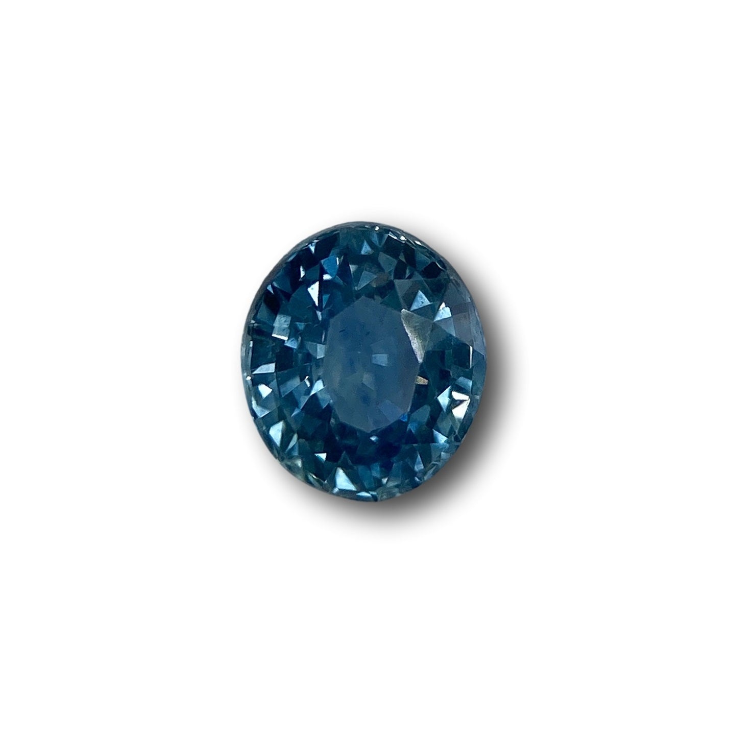 1.15ct oval brilliant cut blue Montana sapphire gemstone with faceted edges on a white background.