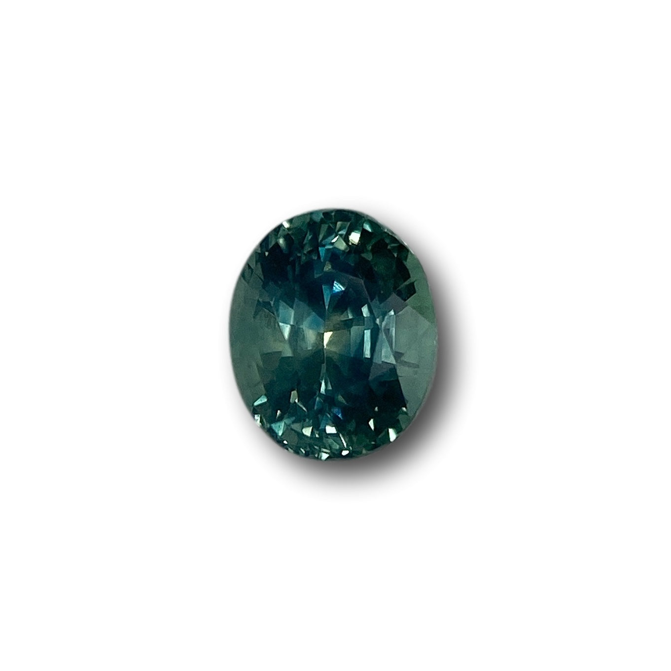 1.15ct oval brilliant cut green Montana sapphire gemstone with deep teal facets.