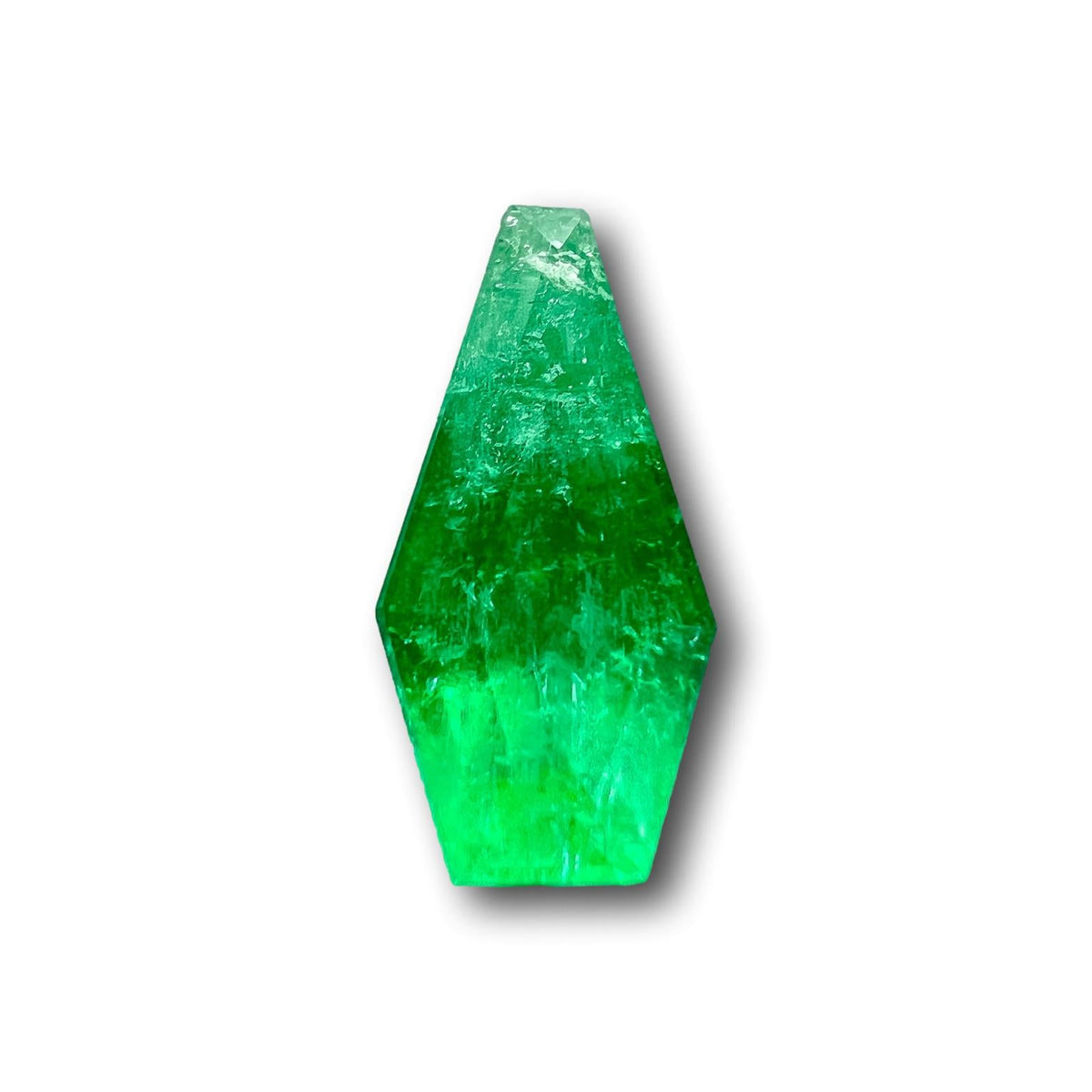 1.15ct Muzo emerald with a step-cut shield shape and vibrant green color isolated on white.