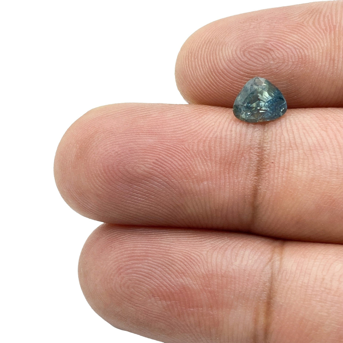 1.16ct pear-shaped blue Montana sapphire with a brilliant cut held between two fingers.