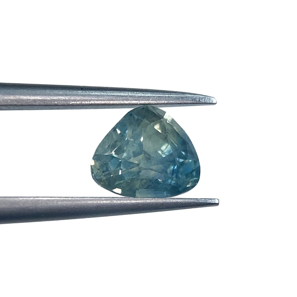 1.16ct brilliant cut pear-shaped blue Montana sapphire held in metal tweezers against a white background.