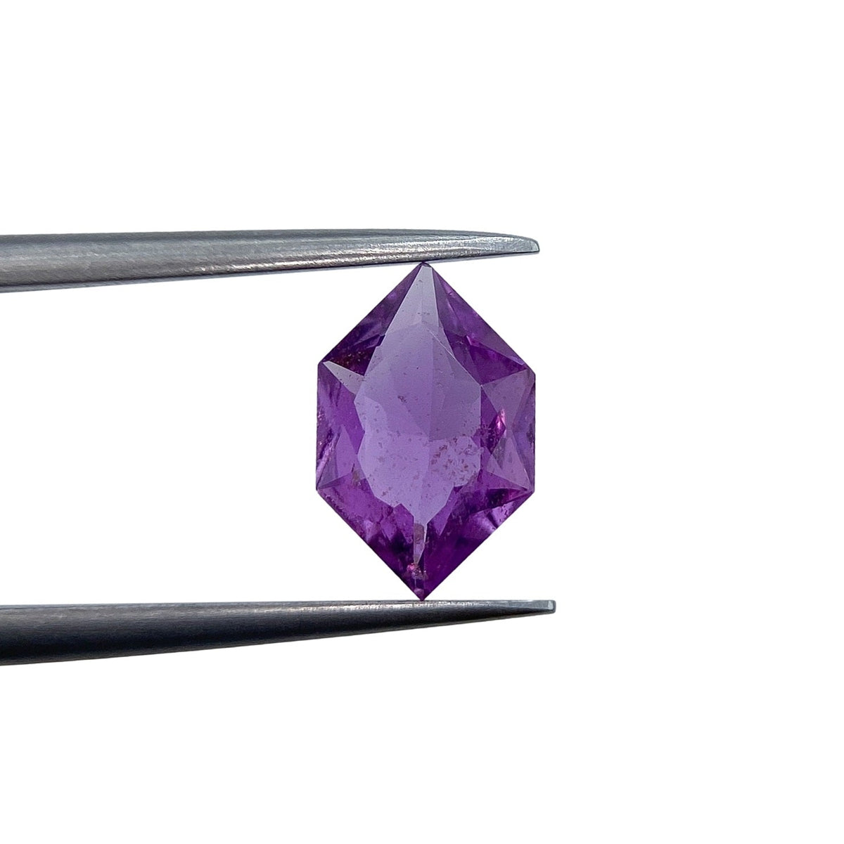 1.17ct brilliant cut violet sapphire in a unique hexagon shape held by metal tweezers against a white background.