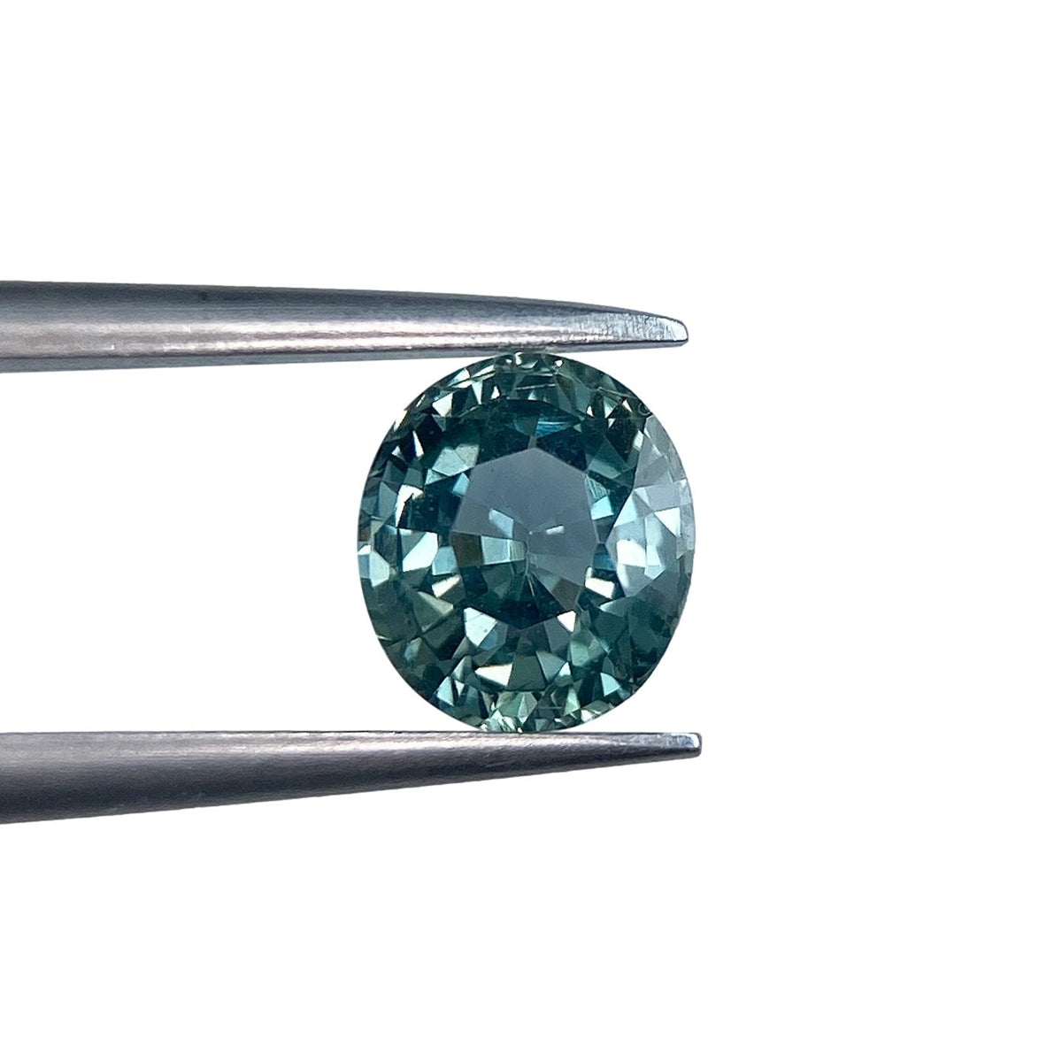 1.17ct oval brilliant cut blue Montana sapphire held in metal tweezers against a white background.