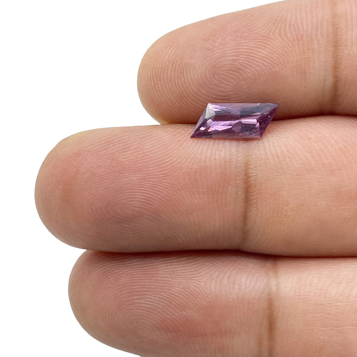 1.18ct brilliant cut violet sapphire with a unique rhomboid shape held between fingers.