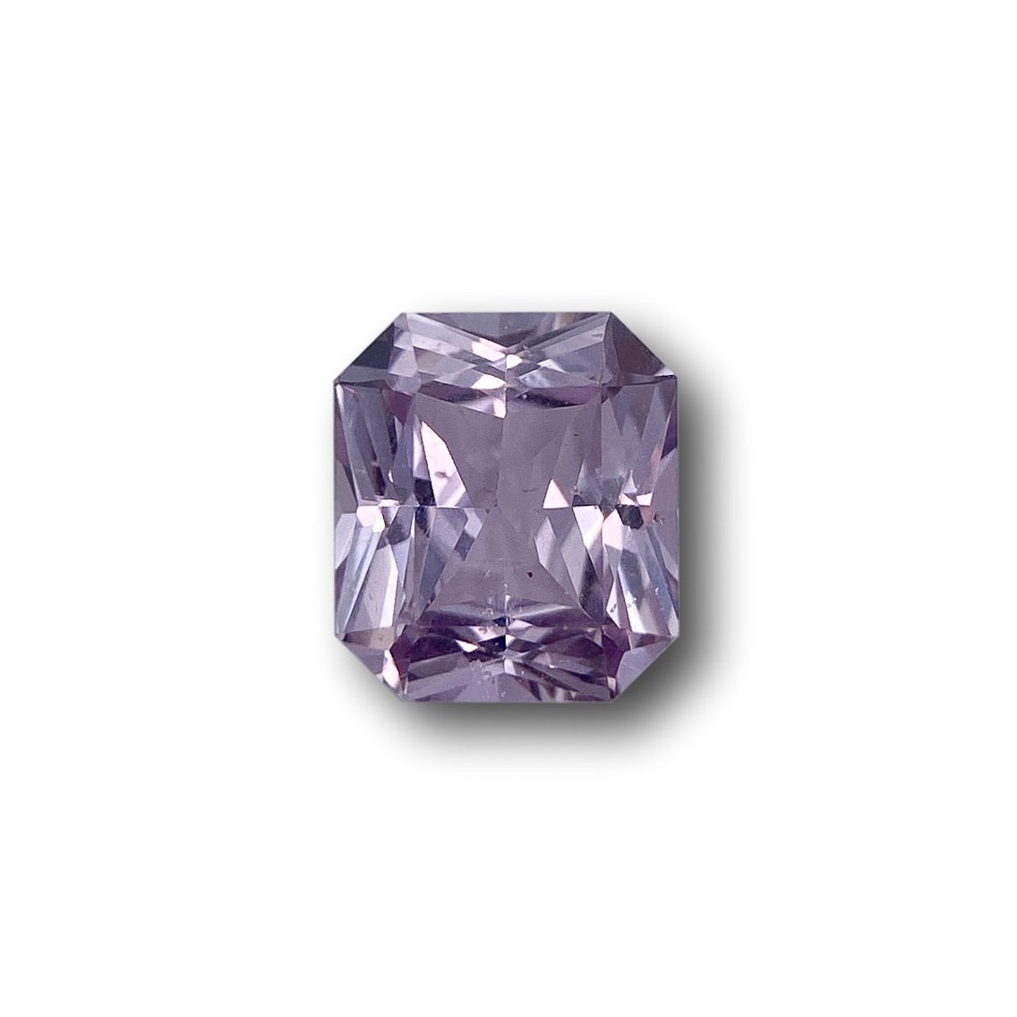 1.25ct radiant cut pink sapphire gemstone with a faceted rectangular design on a white background.