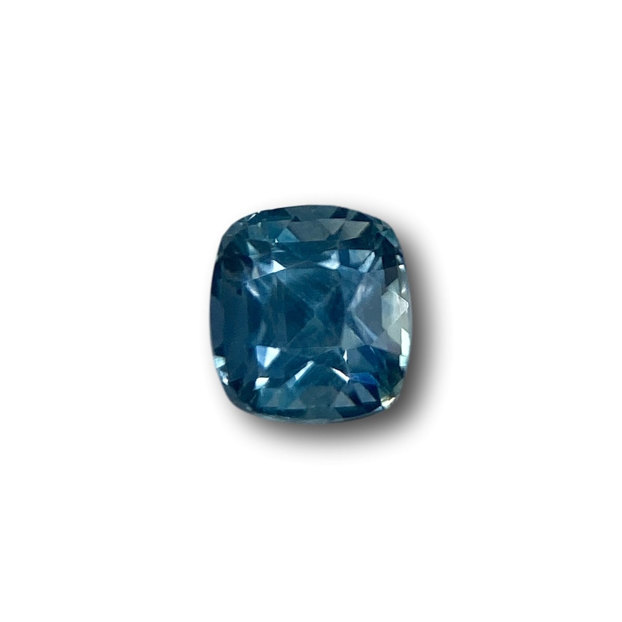 1.26ct cushion-cut blue Montana sapphire with a brilliant facet pattern on a white background.