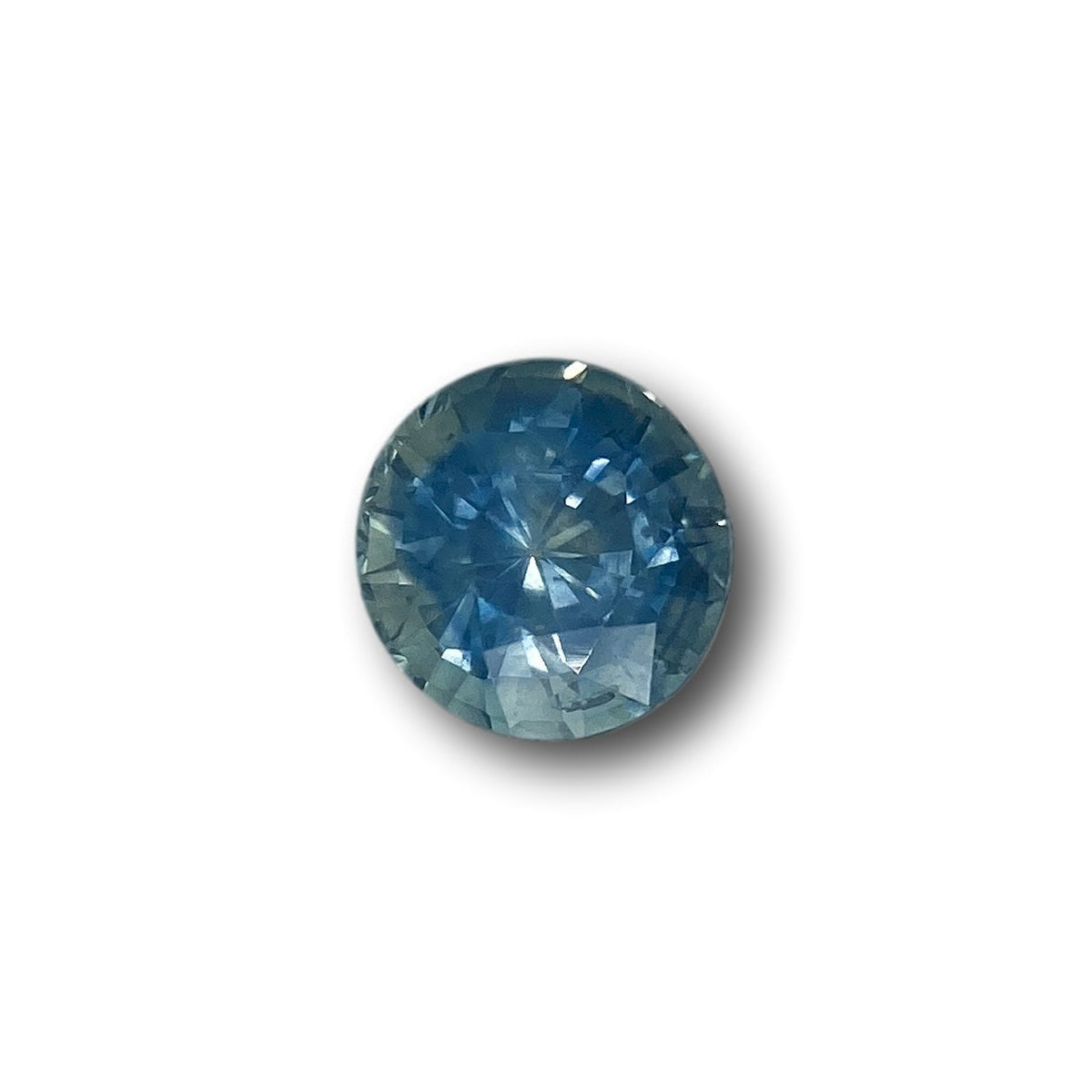 1.28ct round brilliant cut blue Montana sapphire gemstone with faceted surface on a white background.