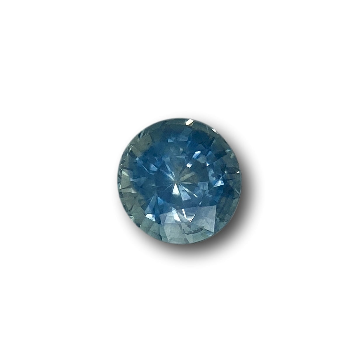 1.28ct round brilliant cut blue Montana sapphire gemstone with faceted surface on a white background.