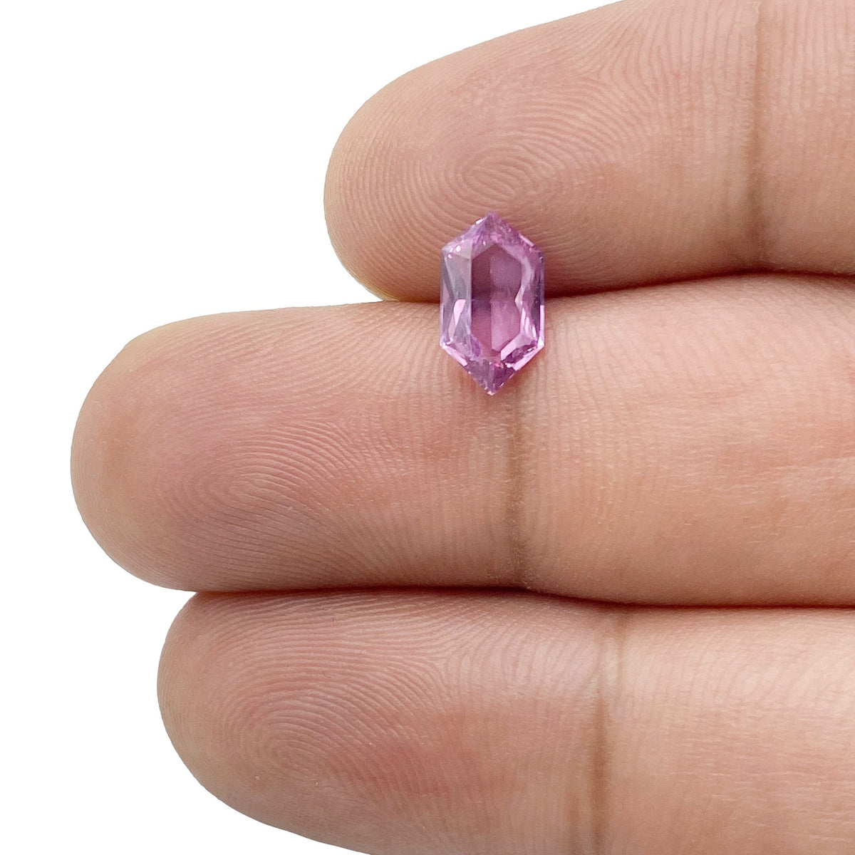 1.31ct brilliant cut violet sapphire in a unique hexagon shape held between fingers.