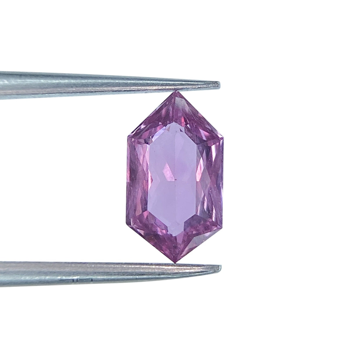 1.31ct brilliant cut violet sapphire in a unique hexagon shape held by metal tweezers.