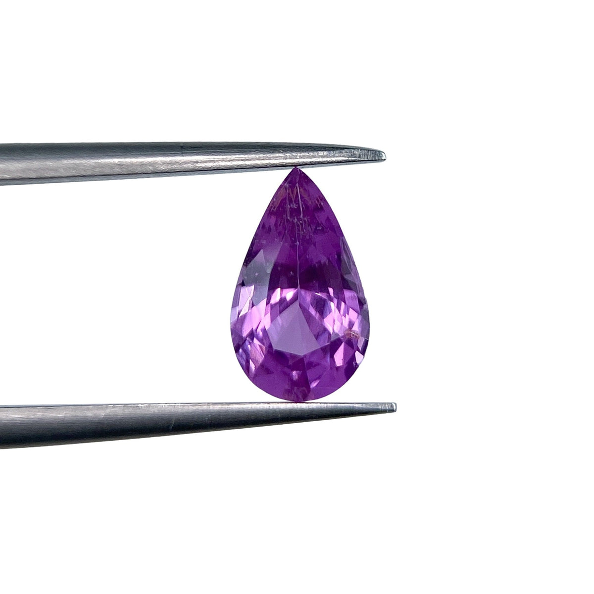 1.32ct brilliant cut pear-shaped violet sapphire held by metal tweezers against a white background.