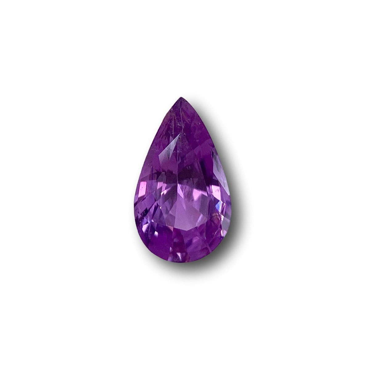 1.32ct brilliant cut pear-shaped violet sapphire gemstone with faceted surface on a white background.
