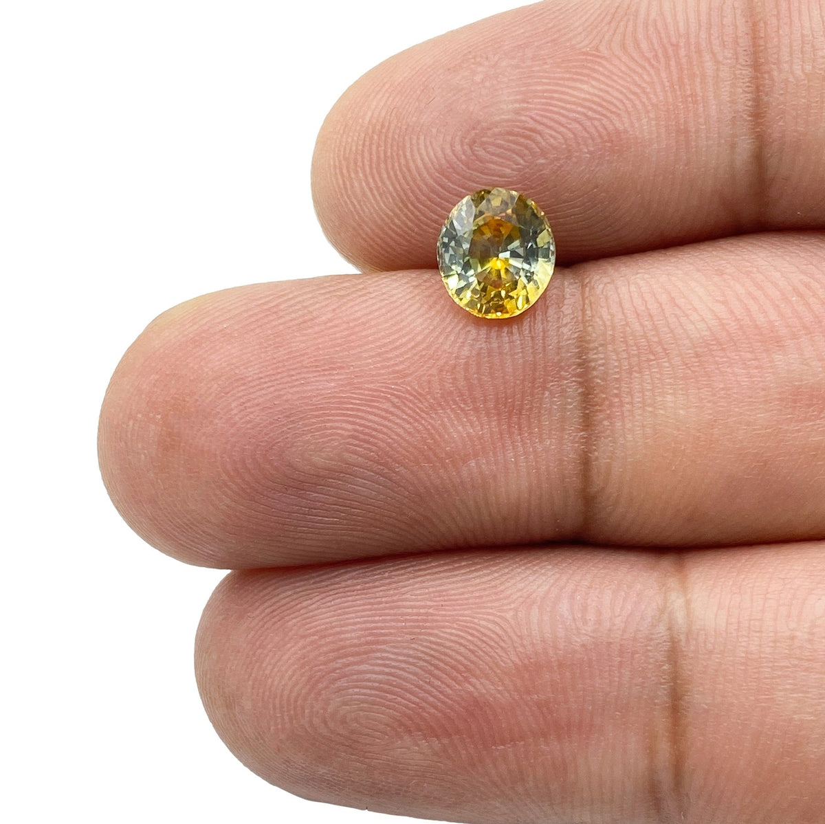 1.42ct oval brilliant cut yellow Montana sapphire held between two fingers.