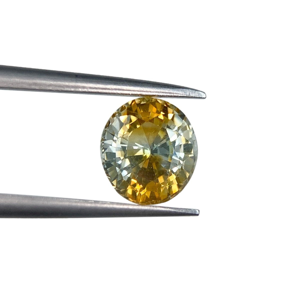 1.42ct oval brilliant cut yellow Montana sapphire held in metal tweezers against a white background.
