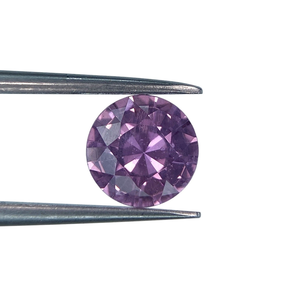 1.44ct round brilliant cut violet sapphire held in metal tweezers against a white background.