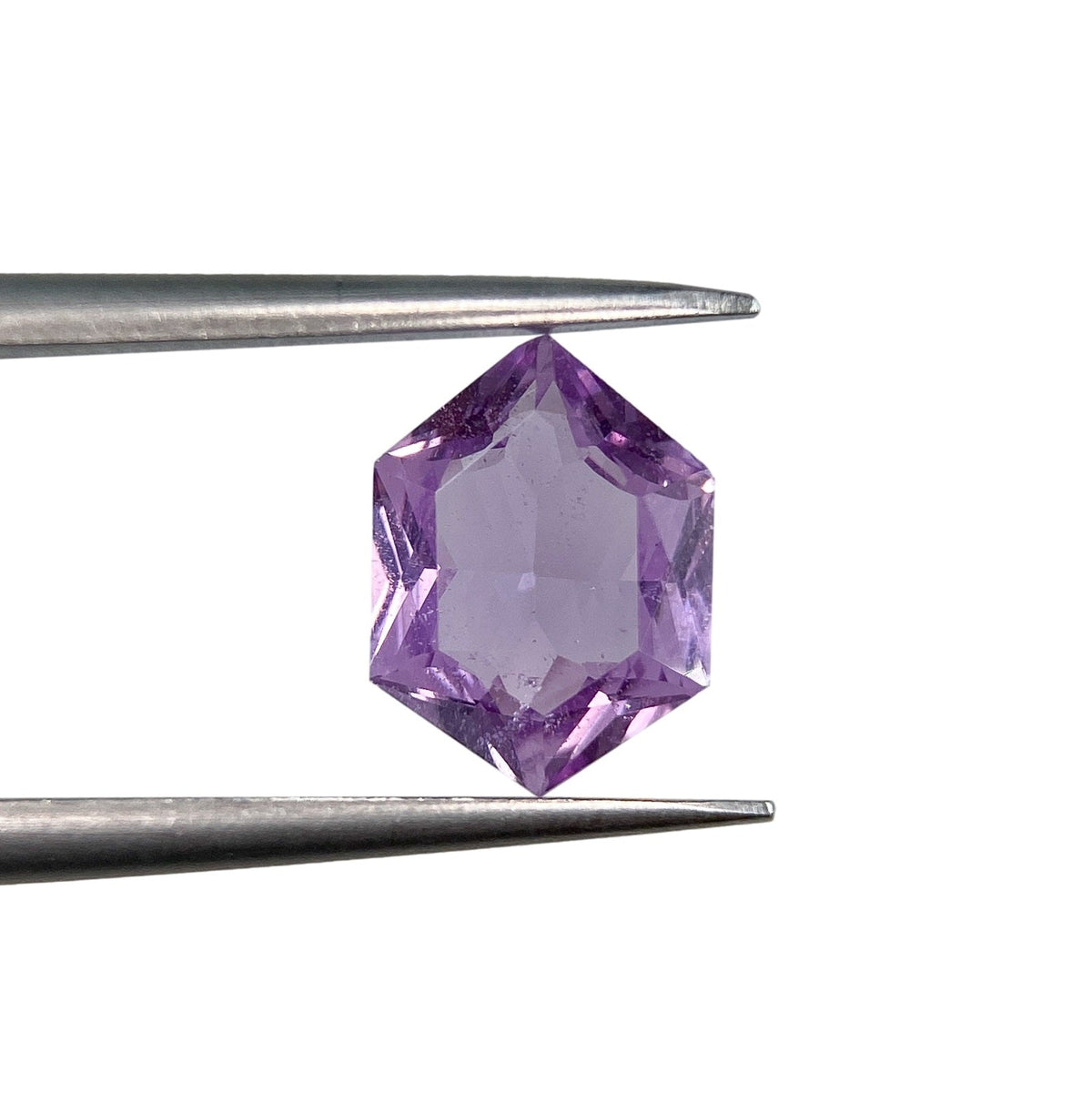 1.45ct brilliant cut violet sapphire in a unique hexagon shape held by metal tweezers against a white background.