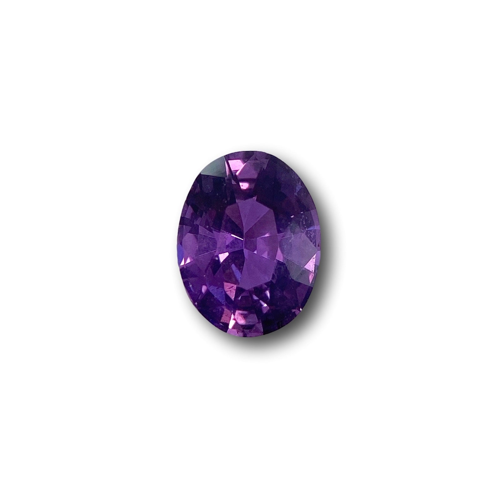 1.58ct oval brilliant cut violet sapphire gemstone with deep purple facets on a white background.