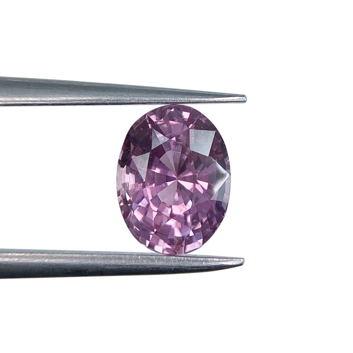 1.59ct oval brilliant cut violet sapphire held in metal tweezers against a white background.