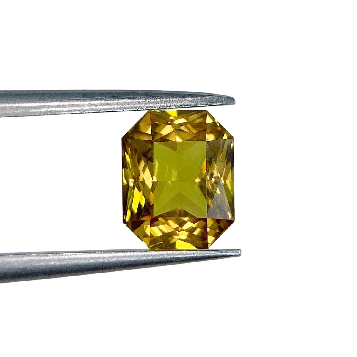 1.62ct radiant cut yellow sapphire gemstone held in metal tweezers against a white background.