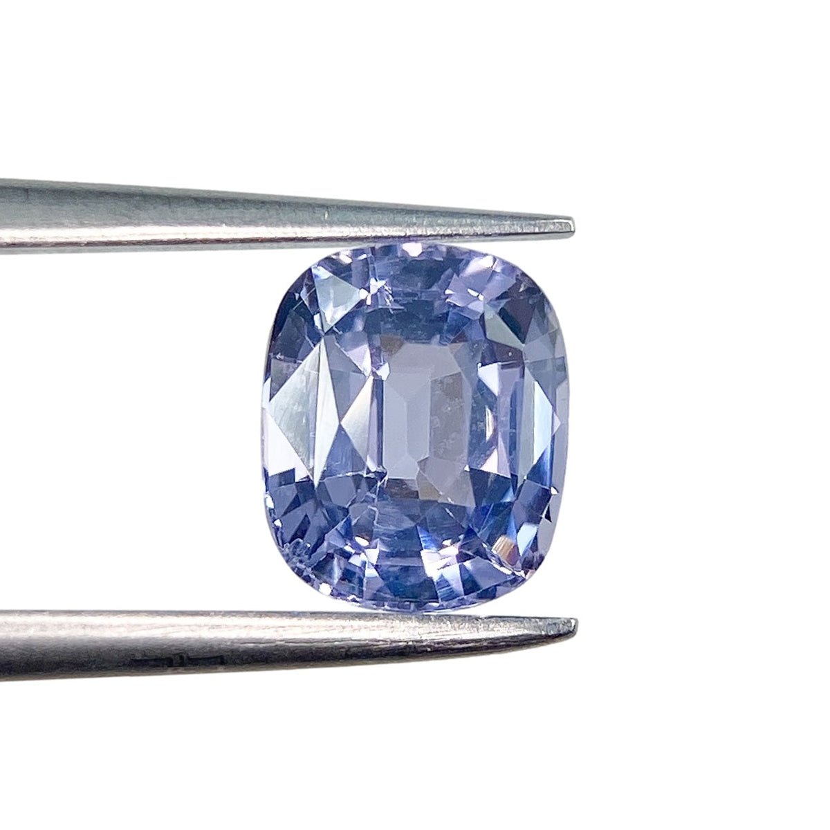 1.64ct brilliant cut cushion-shaped blue spinel gemstone held in metal tweezers against a white background.