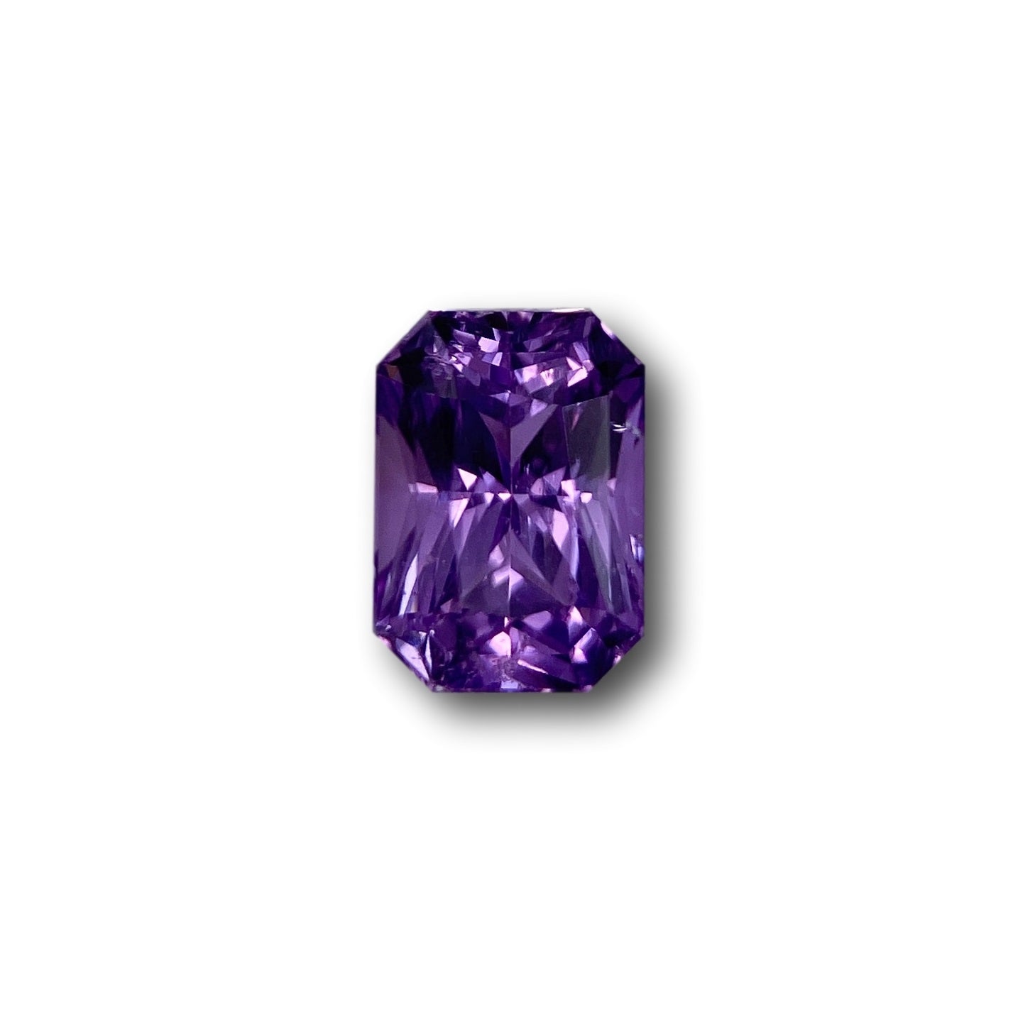1.77ct radiant cut violet sapphire gemstone with brilliant facets isolated on a white background.