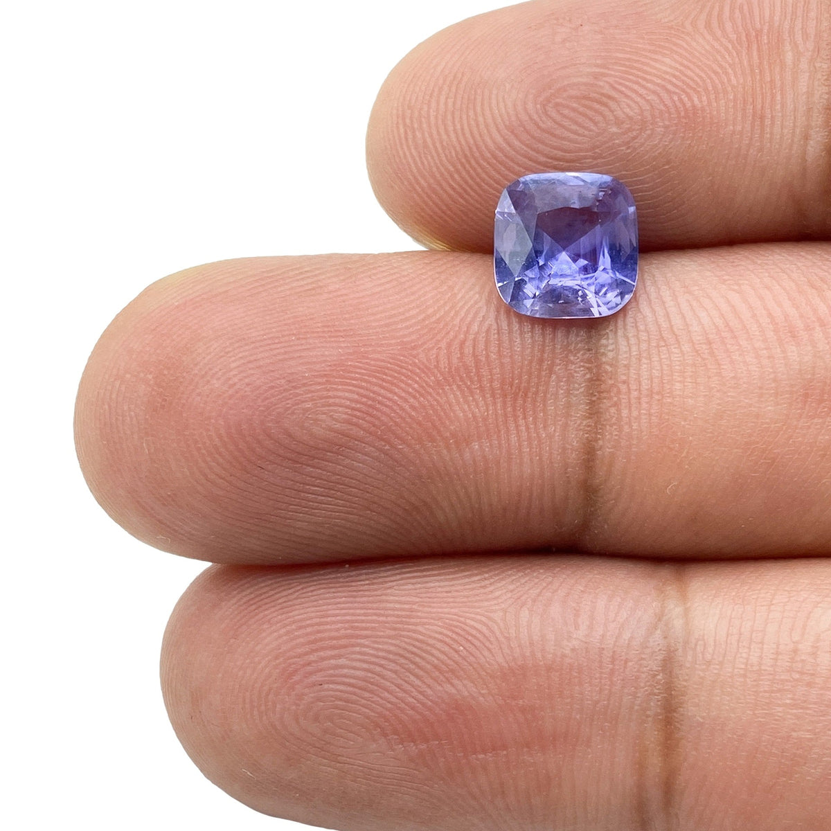 1.80ct brilliant cut cushion-shaped blue sapphire gemstone held between fingers.