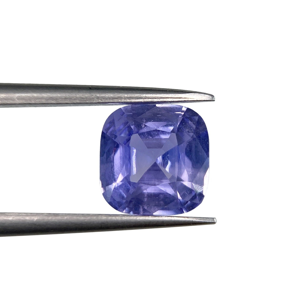 1.80ct brilliant cut cushion-shaped blue sapphire held in metal tweezers against a white background.