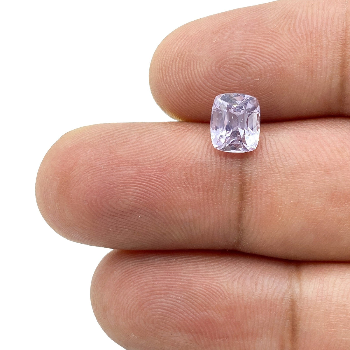 1.81ct brilliant cut cushion-shaped purple sapphire held between fingers.