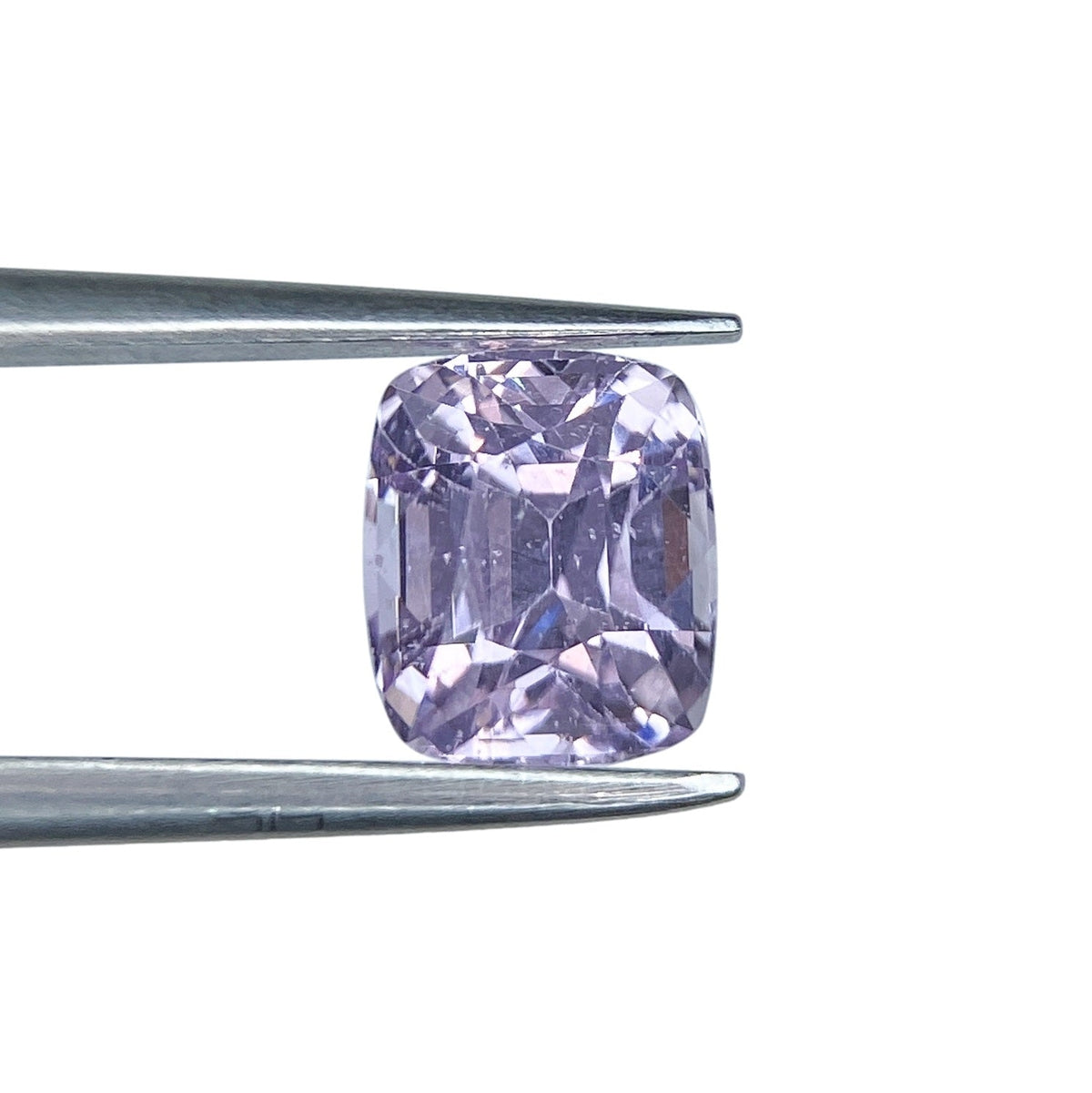 1.81ct brilliant cut cushion-shaped purple sapphire held in metal tweezers against a white background.