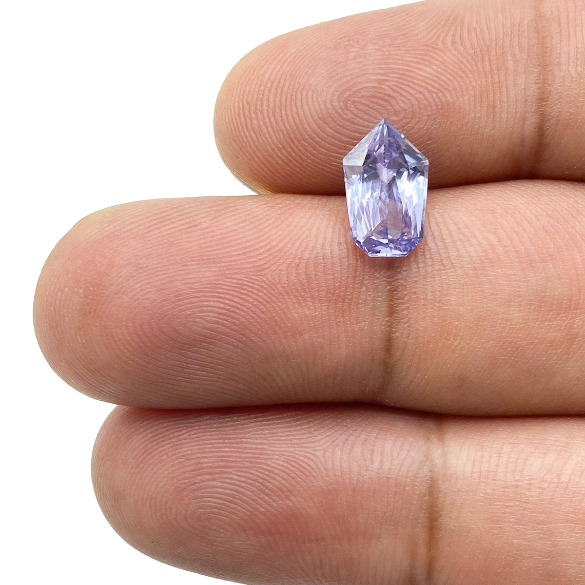 1.96ct brilliant cut shield-shaped blue sapphire gemstone held between fingers, showcasing its faceted design.
