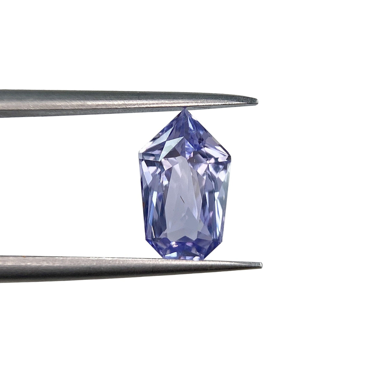 1.96ct brilliant cut blue sapphire in a unique shield shape held by metal tweezers against a white background.