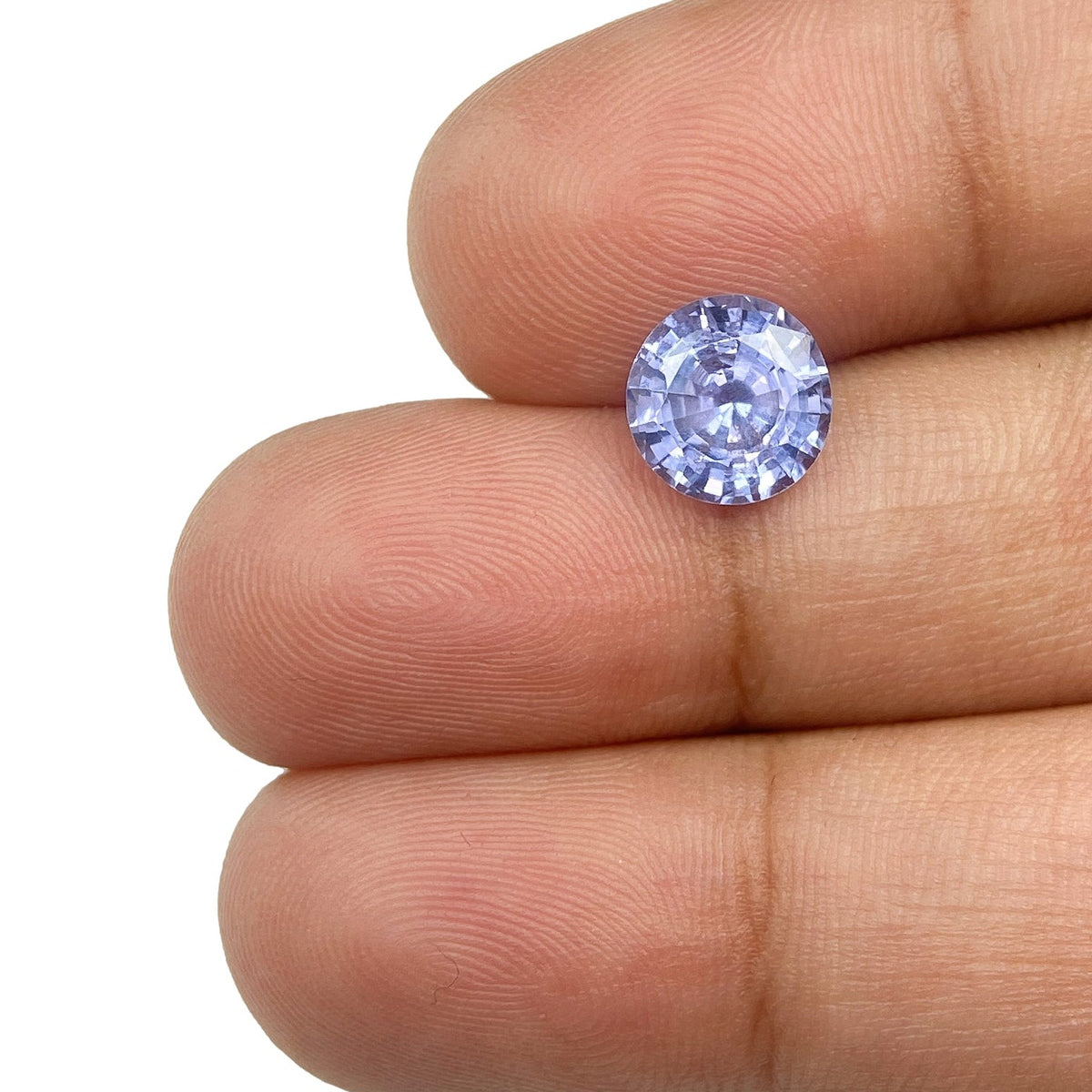 2.05ct round brilliant cut blue sapphire gemstone held between fingers.