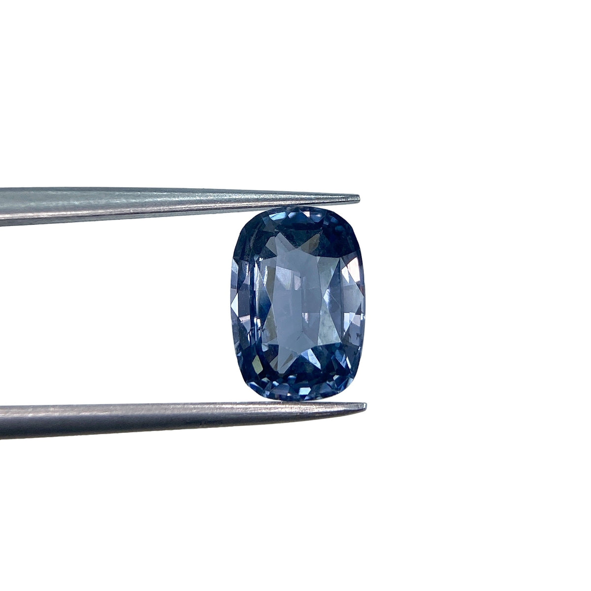 2.39ct brilliant cut cushion-shaped blue spinel gemstone held in metal tweezers against a white background.
