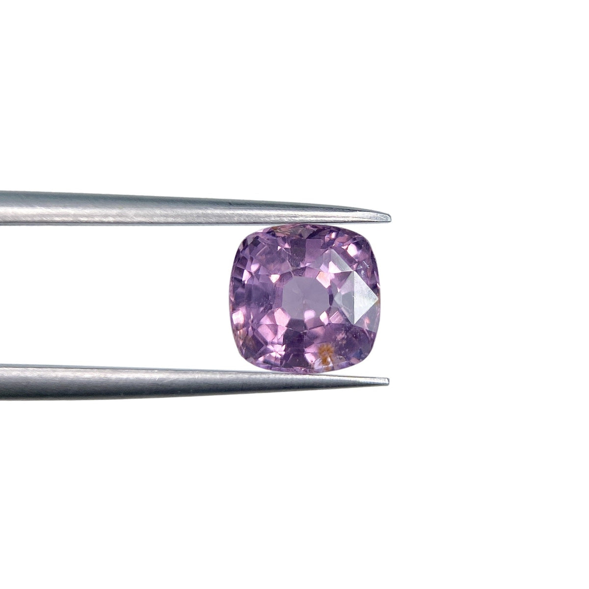 2.57ct cushion-cut violet spinel gemstone held in metal tweezers against a white background.
