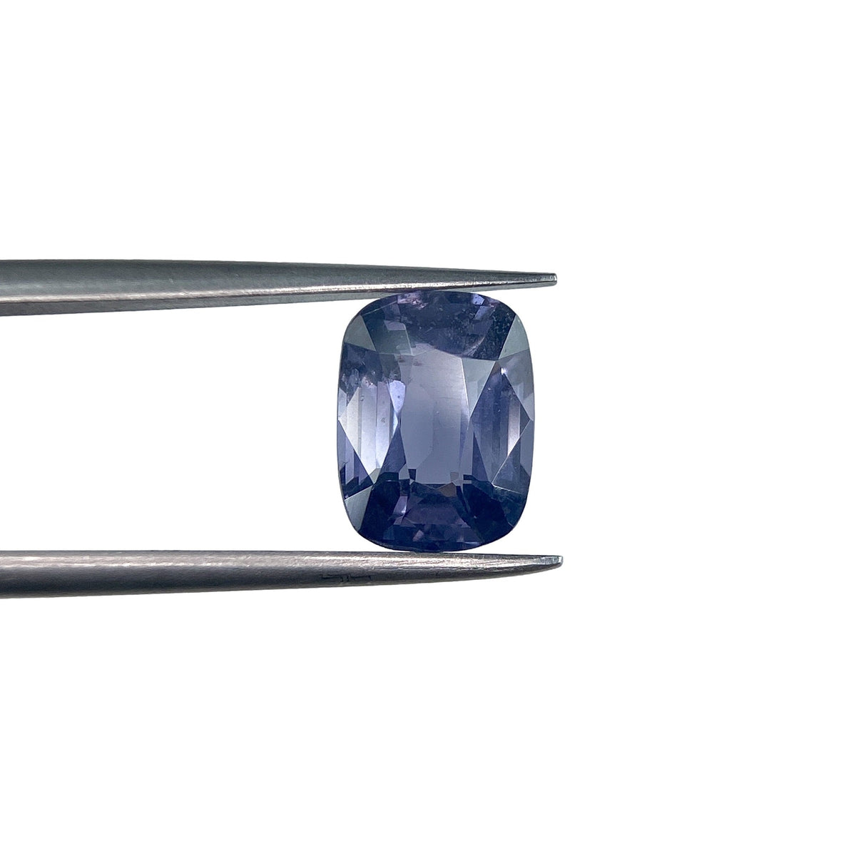 3.07ct cushion-cut blue spinel gemstone held in metal tweezers against a white background.