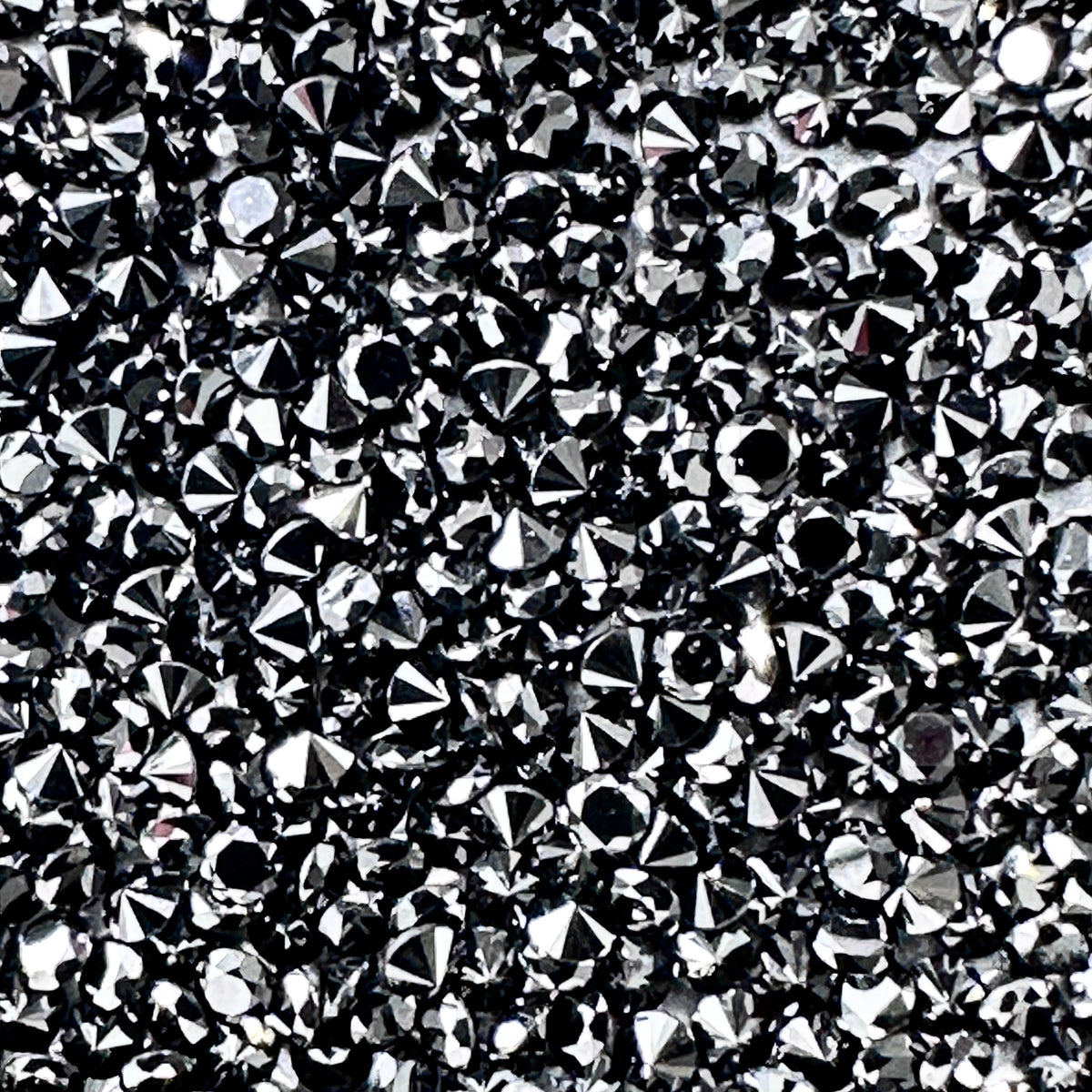 A collection of sparkling, round brilliant-cut black diamond melee stones with high luster and faceted surfaces.